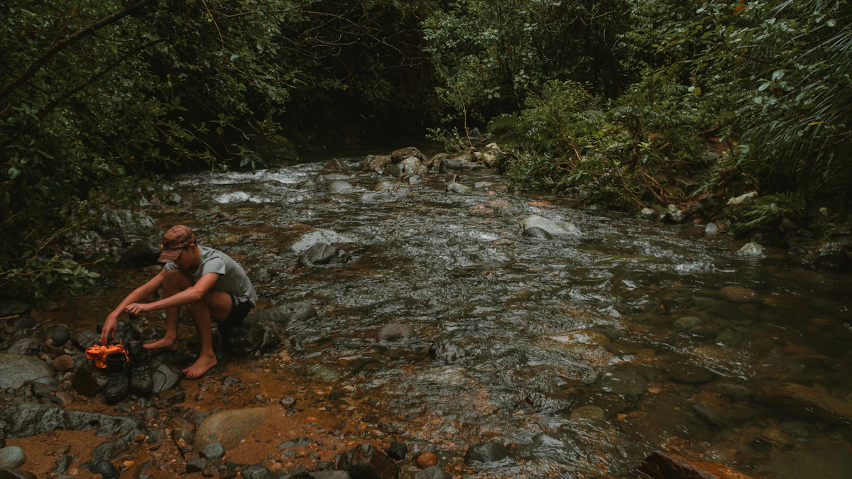 A hiker filling a portable water filter bottle from a clear mountain stream