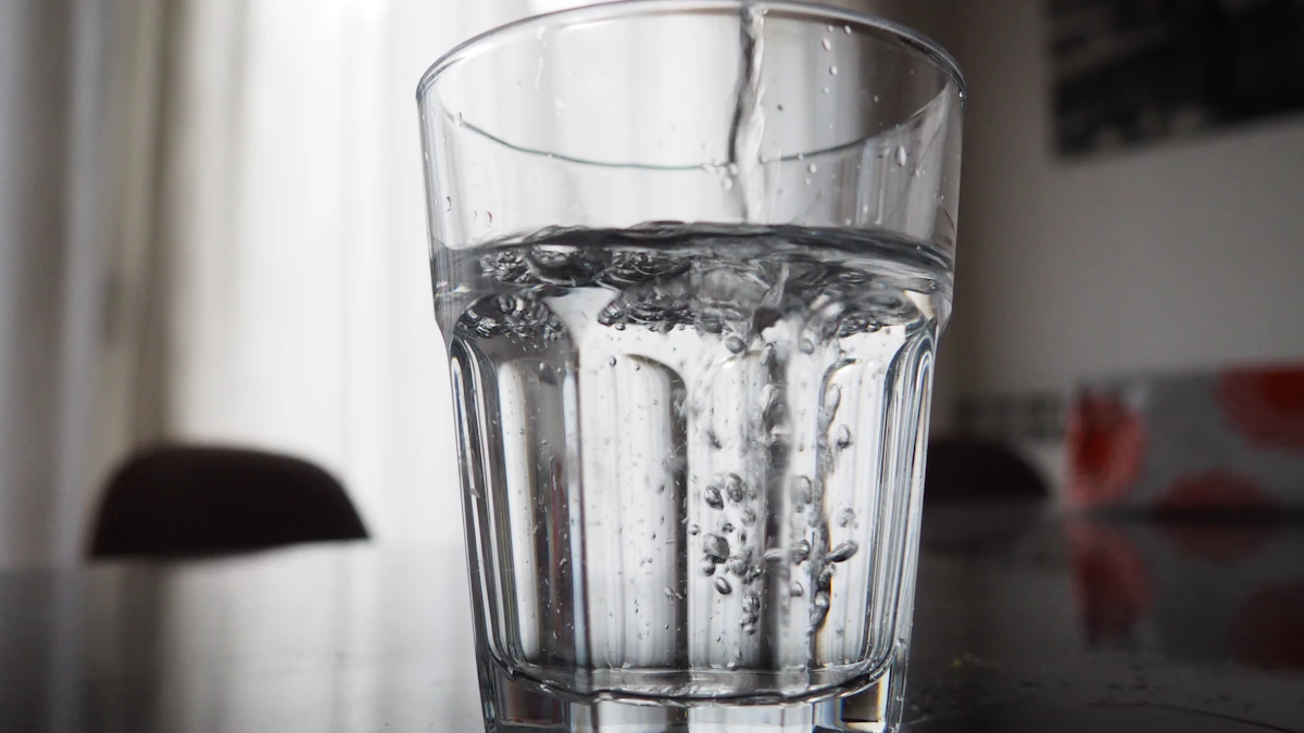 Several water filters lined up on a kitchen counter next to a glass of clear filtered water