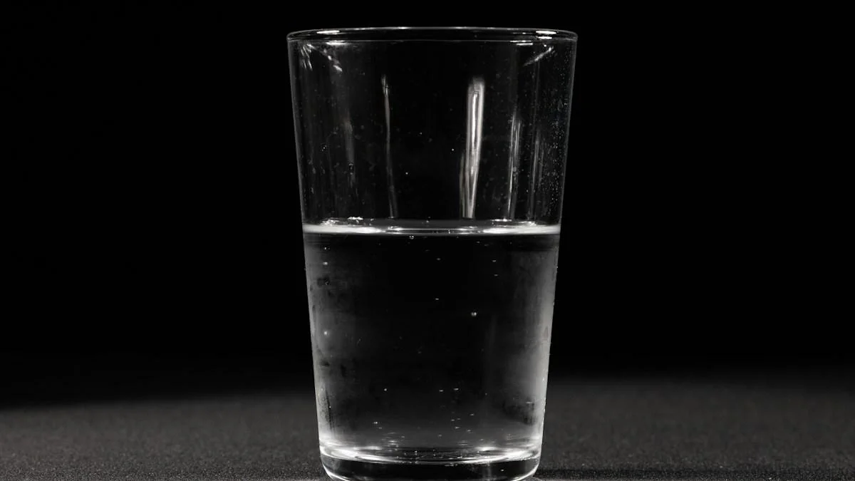 A clear drinking glass about half full of water, with small bubbles clinging to the inside, standing on a dark speckled surface against a black background