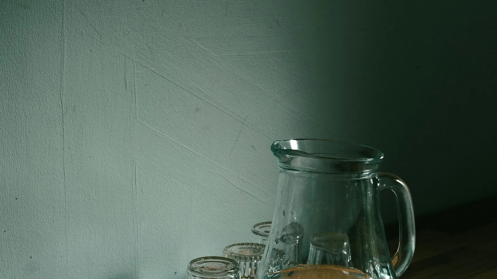 A clear water filter pitcher pouring filtered water into a glass on a kitchen counter